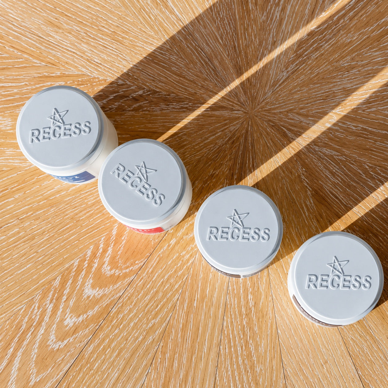 Four blue circular objects with 'Recess' branding on a wooden surface.