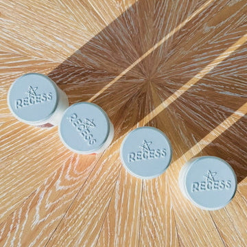 Four blue circular objects with 'Recess' branding on a wooden surface.