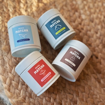 Four containers of matcha on a woven surface